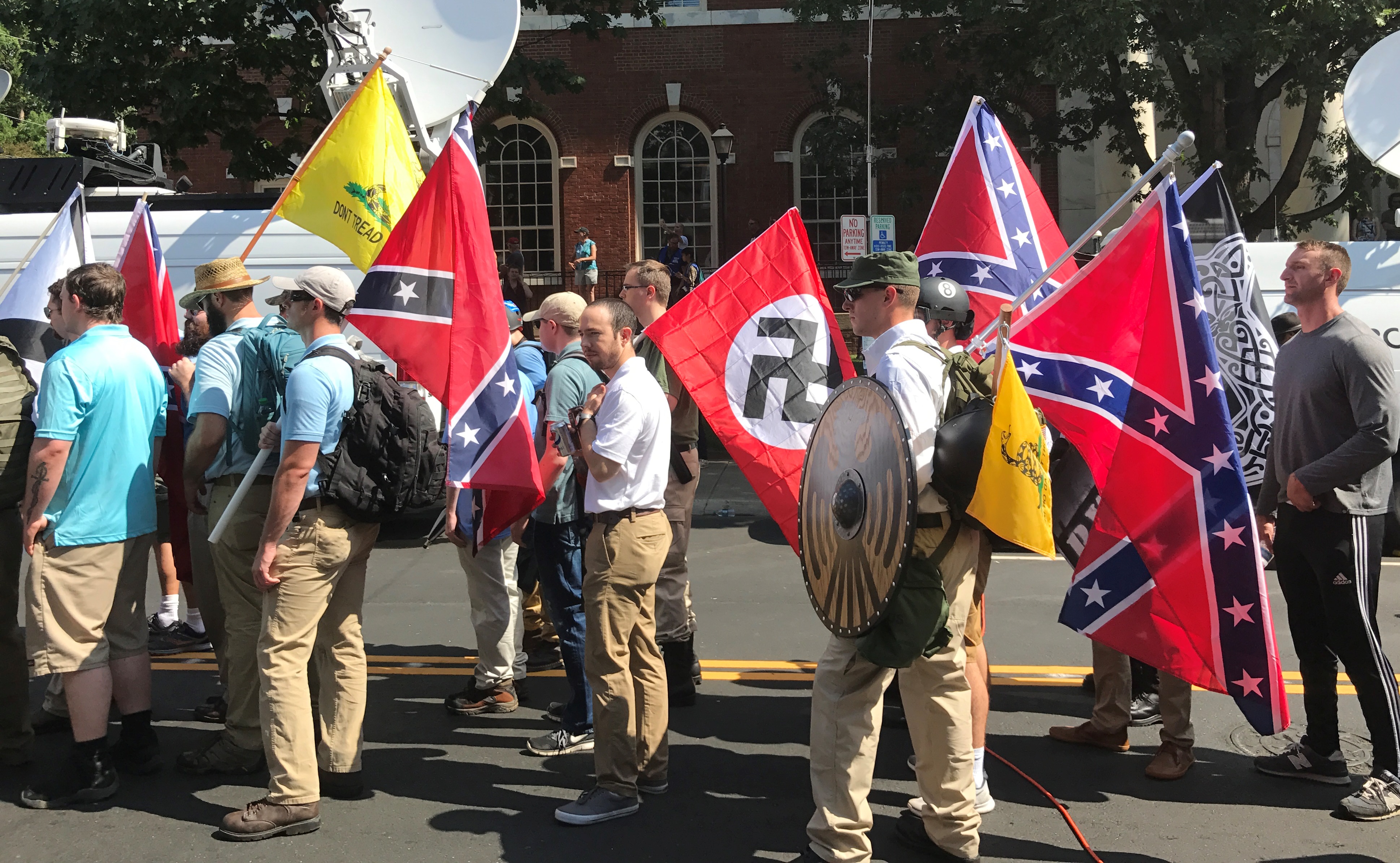 A photo of white supremacists holding swastika and confederate flags.