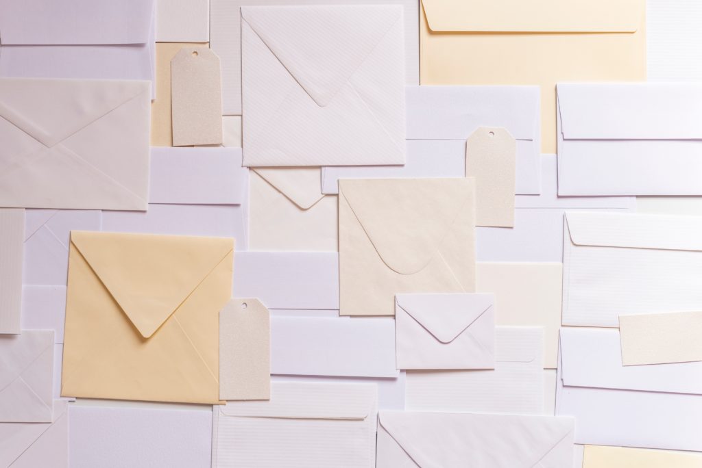 The image is of many shapes and sizes of envelopes in different shades of white.
