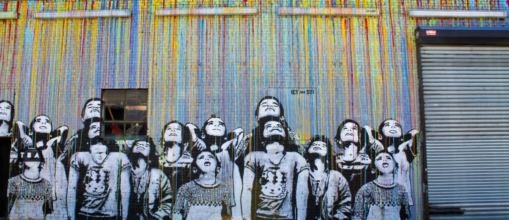 A mural of children with a rainbow of rain coming down on them.