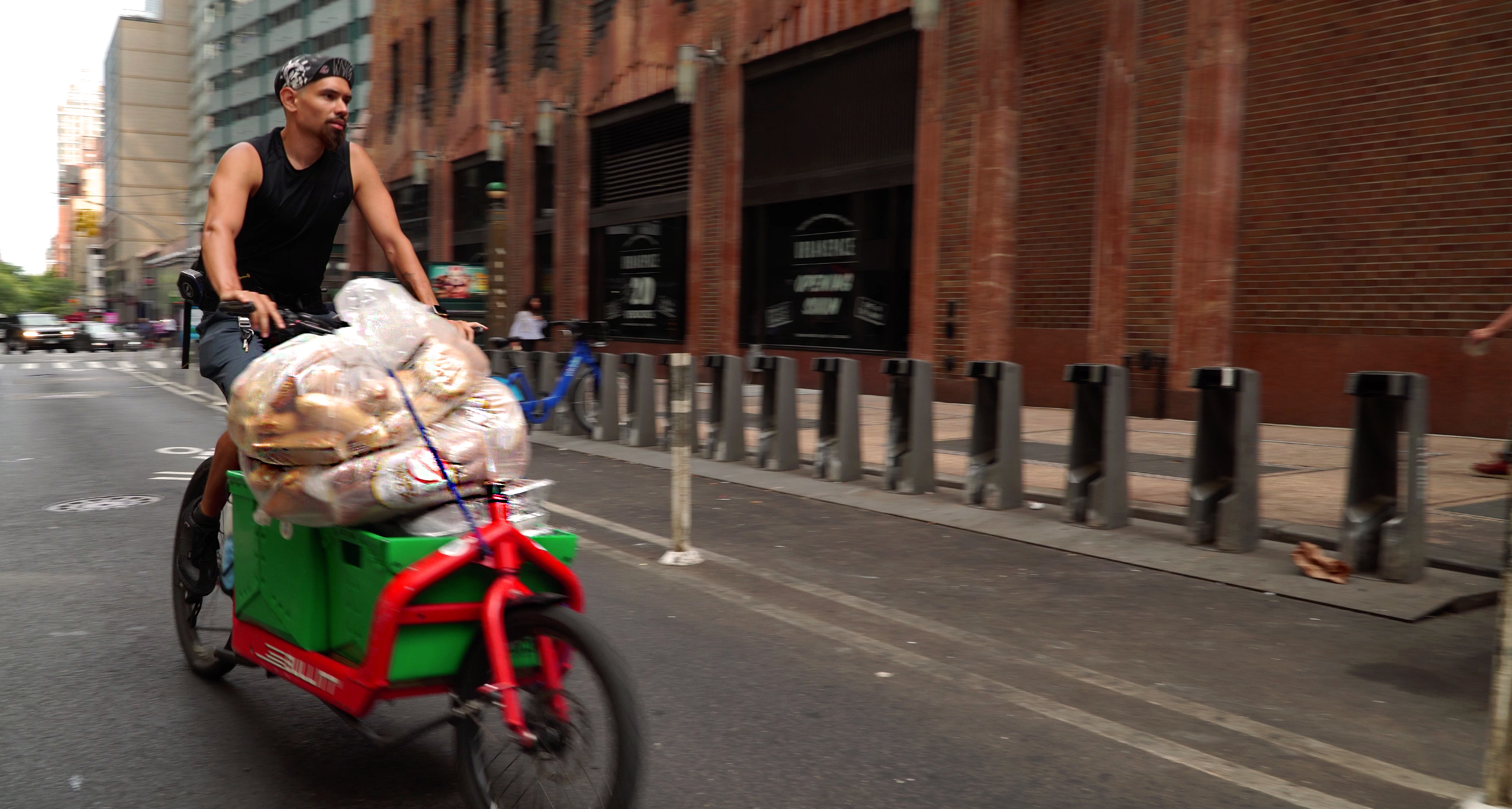 A man on a red bike carrying food in plastic containers.